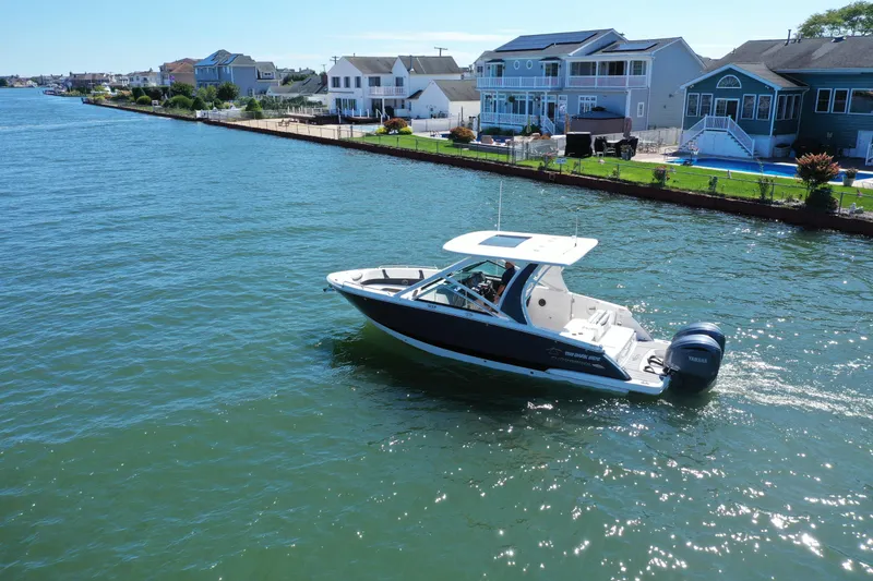 Slide: The Image of 2022 Chaparral 280 OSX boat cruising near waterfront homes on a sunny day. - 39