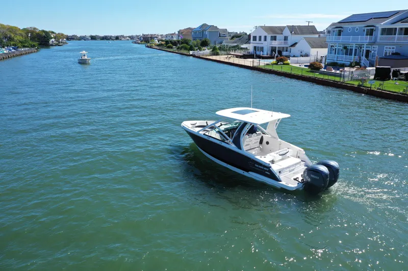 Slide: The Image of 2022 Chaparral 280 OSX boat cruising on a scenic waterway near waterfront homes. - 4