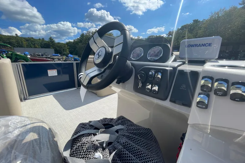 Slide: The Image of 2026 Harris Cruiser 230 CW boat dashboard with steering wheel and control panel under blue sky. - 7