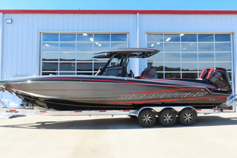 The Image of 2026 Sunsation 32CCX boat with sleek black and red design, parked on a trailer. - 0