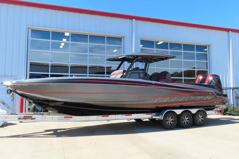 Slide: The Image of 2026 Sunsation 32CCX boat on trailer, parked outside a large garage. - 2