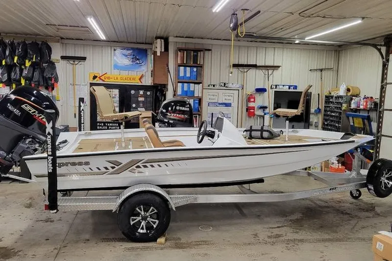 The Image of 2026 Xpress H18 Bass boat in a garage, on a trailer, with Yamaha outboard motor. - 1