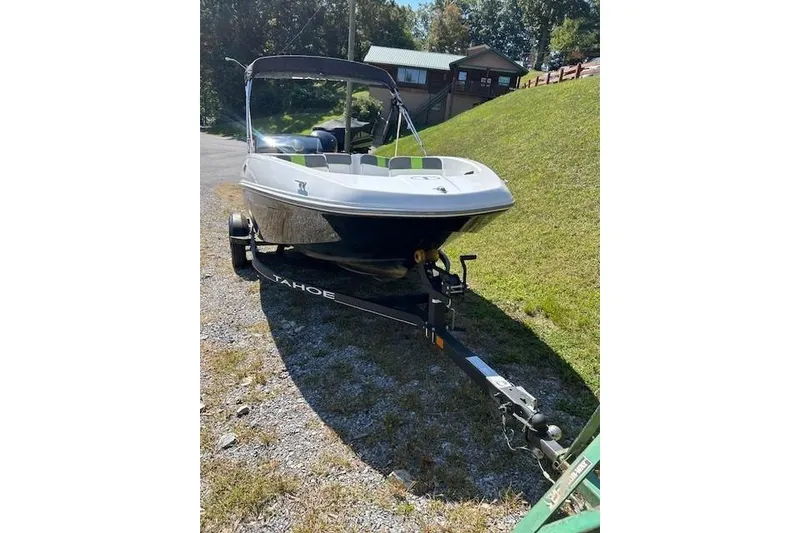 Slide: The Image of 2021 Tahoe T16 boat on trailer, parked on grassy area near a house. - 4