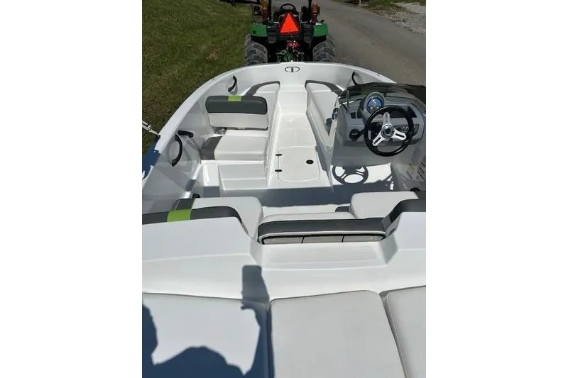 Slide: The Image of 2021 Tahoe T16 boat interior with seating and steering wheel, parked on grass. - 7