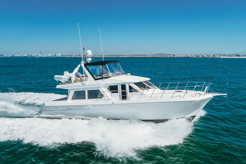 Slide: The Image of 2003 Navigator 53 yacht cruising on blue ocean with city skyline in background. - 0