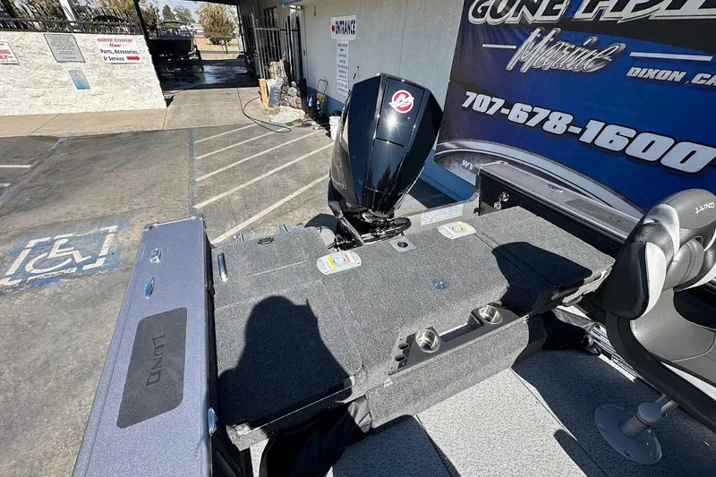 Slide: The Image of 2025 Lund 1875 Pro-V boat with motor, parked at a marine service center. - 13