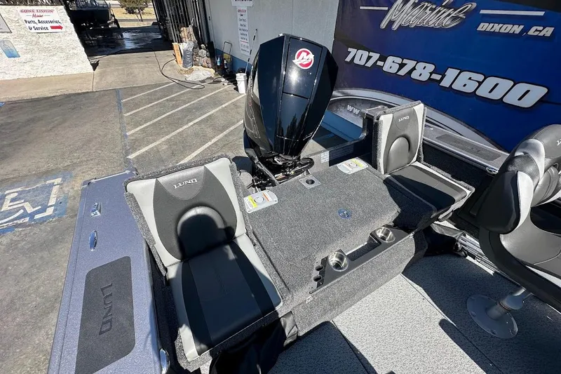 Slide: The Image of 2025 Lund 1875 Pro-V boat interior with seating and motor, displayed at a marine dealership. - 14