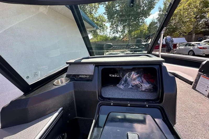 Slide: The Image of 2025 Lund 1875 Pro-V boat interior with storage compartment and windshield view. - 18
