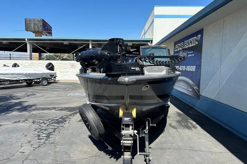 Slide: The Image of 2025 Lund 1875 Pro-V boat on trailer, parked outdoors near a marine dealership. - 3