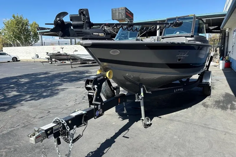 Slide: The Image of 2025 Lund 1875 Pro-V boat on trailer, parked outdoors, featuring Minn Kota trolling motor. - 4