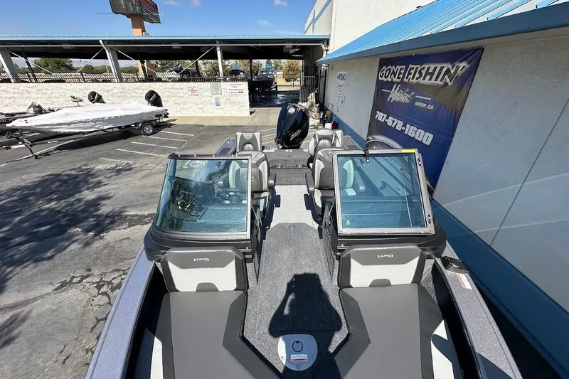 Slide: The Image of 2025 Lund 1875 Pro-V fishing boat parked at dealership with blue awning. - 40