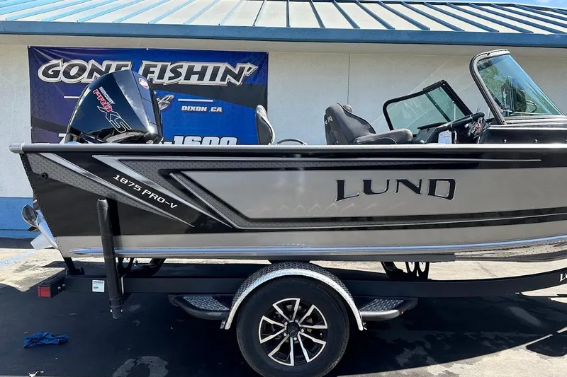 Slide: The Image of 2025 Lund 1875 Pro-V boat on trailer, displayed outdoors with a promotional banner. - 6