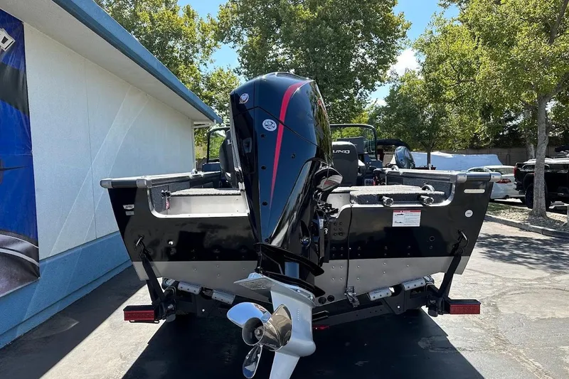 Slide: The Image of 2025 Lund 1875 Pro-V boat with outboard motor, parked outdoors on a sunny day. - 9