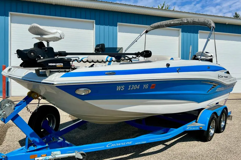 Slide: The Image of 2020 Crownline Eclipse E205 XS Fish boat on trailer, blue and white design, parked outdoors. - 11