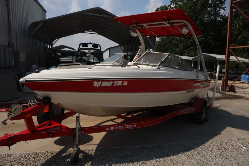 Slide: The Image of 2008 Stingray 195 LS/LX/LR boat with red accents on a trailer in a storage area. - 2
