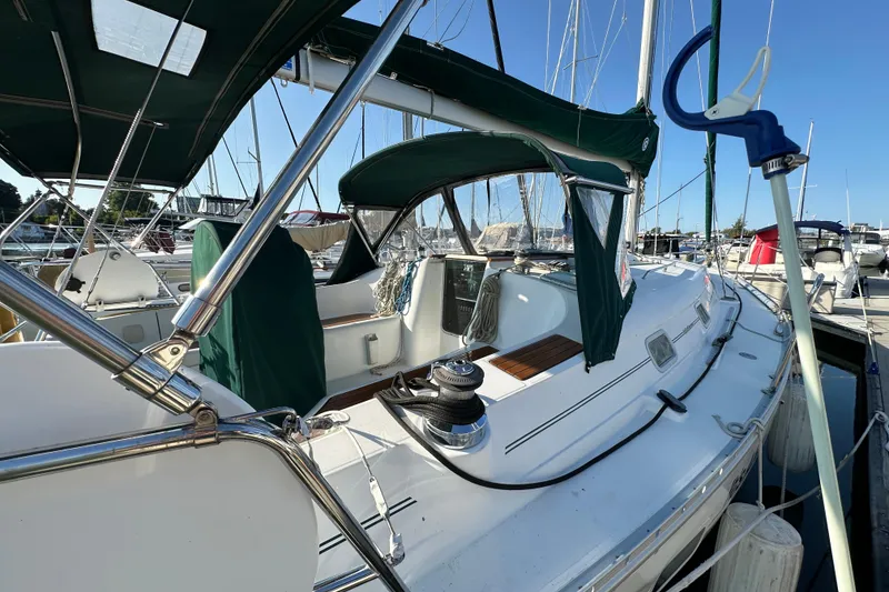 Slide: The Image of 2004 Beneteau 361 sailboat docked, featuring green canopy and sleek white deck design. - 2
