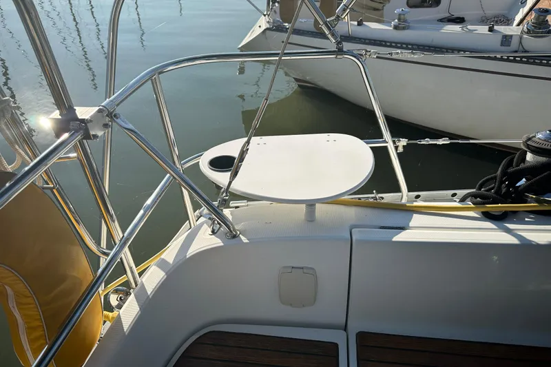 Slide: The Image of 2004 Beneteau 361 sailboat deck with railing and small table, docked in calm waters. - 3