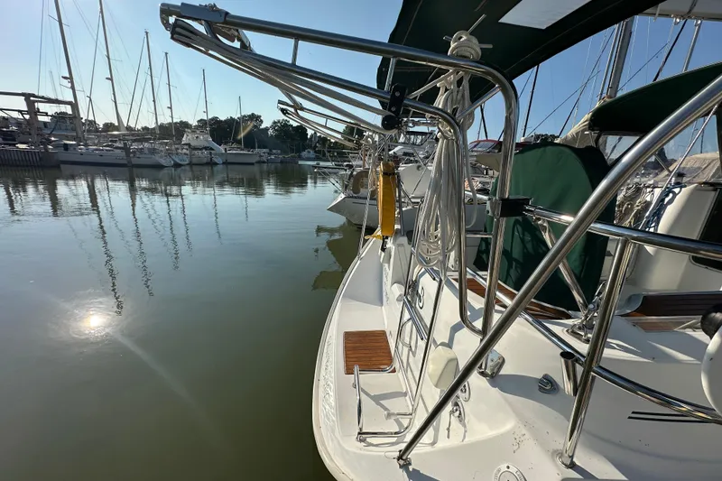 Slide: The Image of 2004 Beneteau 361 sailboat docked in a marina, reflecting sunlight on calm water. - 5