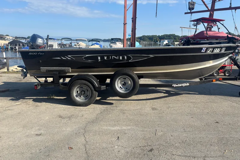Slide: The Image of 2013 Lund 1600 Fury Tiller boat on trailer at marina, sunny day. - 0