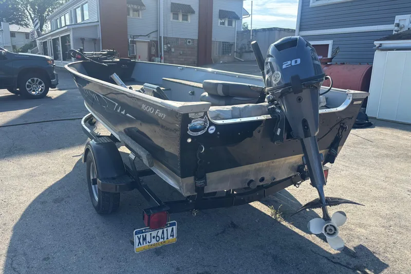 Slide: The Image of 2013 Lund 1600 Fury Tiller boat on trailer with outboard motor in driveway. - 1