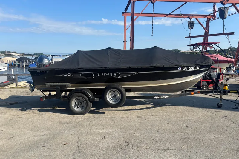 Slide: The Image of 2013 Lund 1600 Fury Tiller boat on trailer, covered, near waterfront. - 10