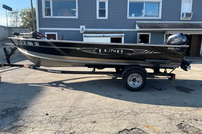 Slide: The Image of 2013 Lund 1600 Fury Tiller boat on trailer, parked outside a building. - 2
