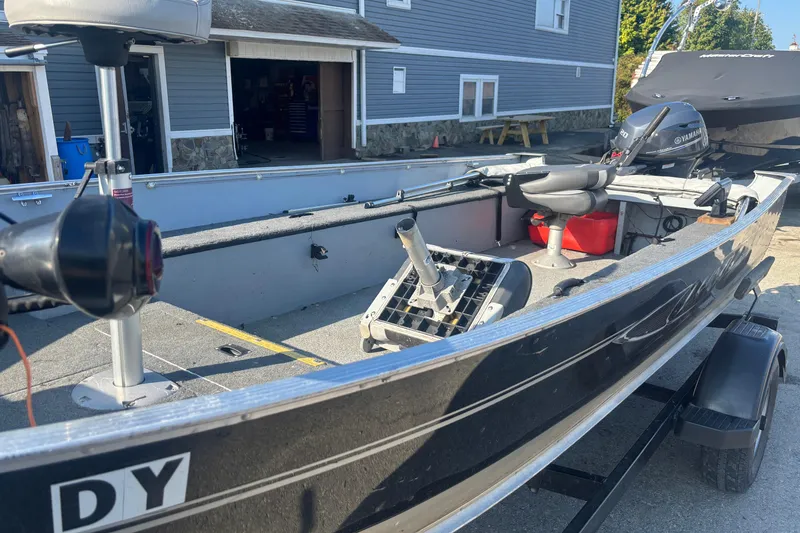Slide: The Image of 2013 Lund 1600 Fury Tiller boat with Yamaha motor, parked near a blue building. - 4