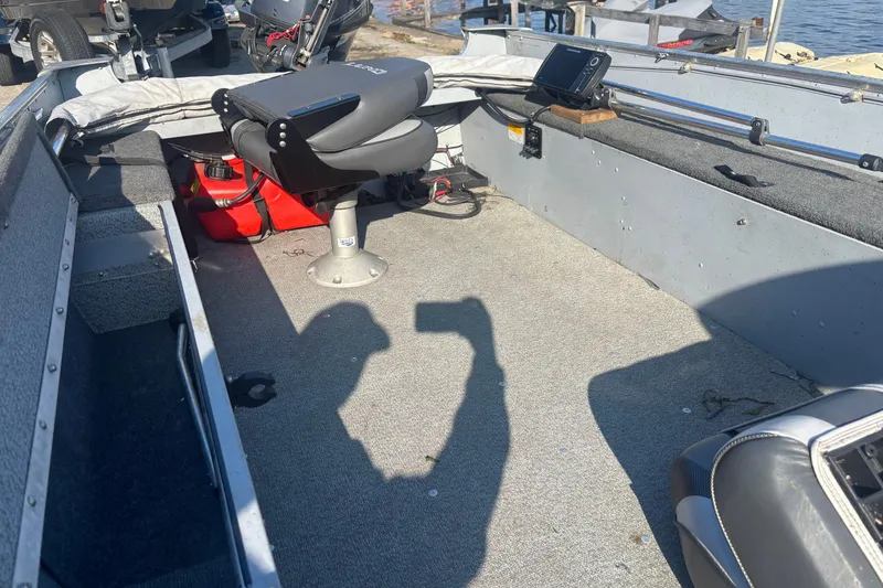 Slide: The Image of 2013 Lund 1600 Fury Tiller boat interior with seating and equipment, docked by the water. - 6