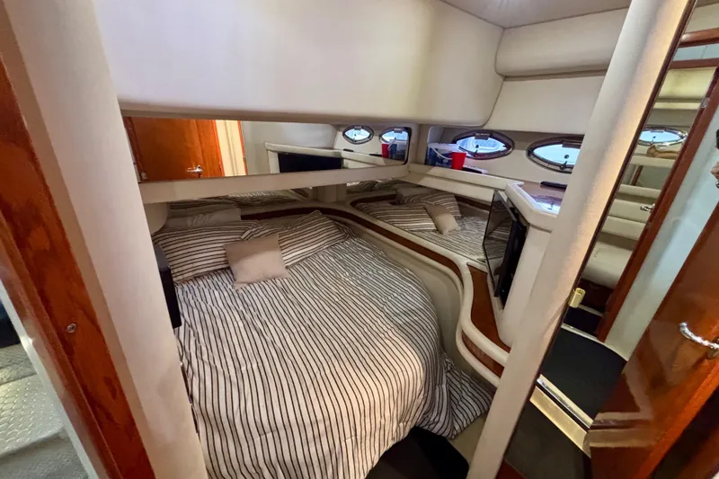 Slide: The Image of 2003 Sea Ray 480 Sedan Bridge cabin interior with striped bedding and porthole windows. - 36