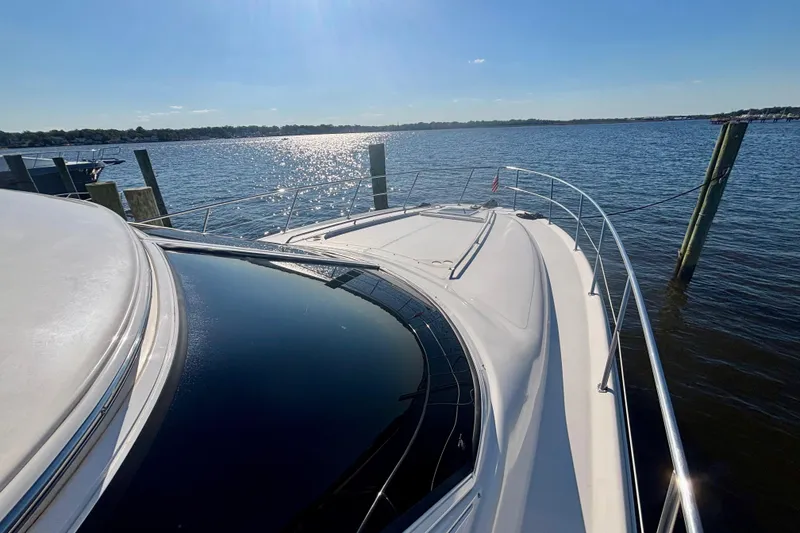 Slide: The Image of 2003 Sea Ray 480 Sedan Bridge yacht docked on a sunny day, overlooking calm waters. - 8