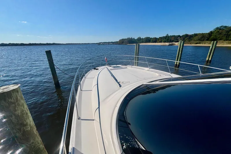 Slide: The Image of 2003 Sea Ray 480 Sedan Bridge yacht docked on a sunny day, scenic water view. - 9