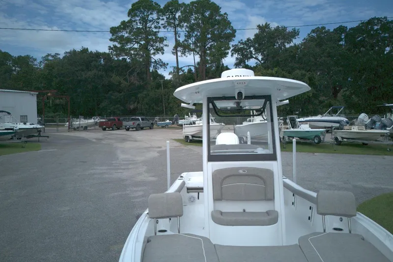 Slide: The Image of 2025 Sea Hunt BX 25 FS boat in a marina with surrounding trees and vehicles. - 3