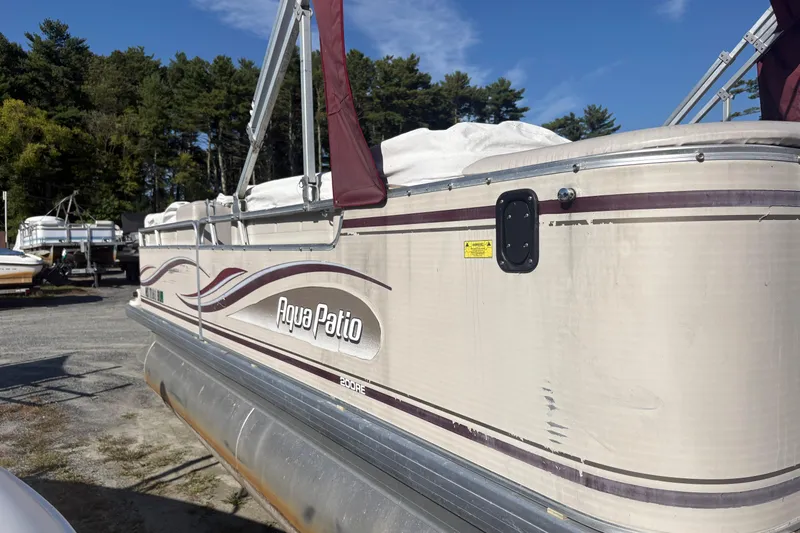 Slide: The Image of 2003 Aqua Patio 200RE pontoon boat in storage, surrounded by trees and other boats. - 2