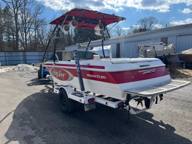 Slide: The Image of 1999 MasterCraft XStar boat with red and white design, parked outdoors on a trailer. - 13