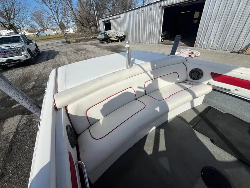 Slide: The Image of 1999 MasterCraft XStar boat interior with white and red seating, parked near a metal building. - 6