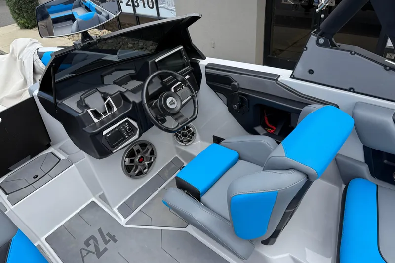 Slide: The Image of 2023 Axis A24 boat interior with blue and gray seating, modern dashboard, and steering wheel. - 13