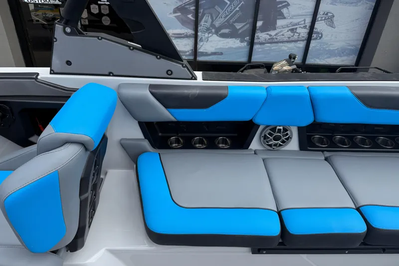 Slide: The Image of 2023 Axis A24 boat interior with blue and gray seating, featuring cup holders and speaker. - 15