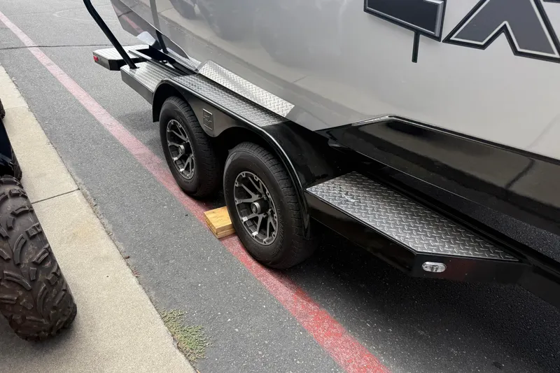 Slide: The Image of 2023 Axis A24 trailer with dual wheels parked on a street, supported by a wooden block. - 17