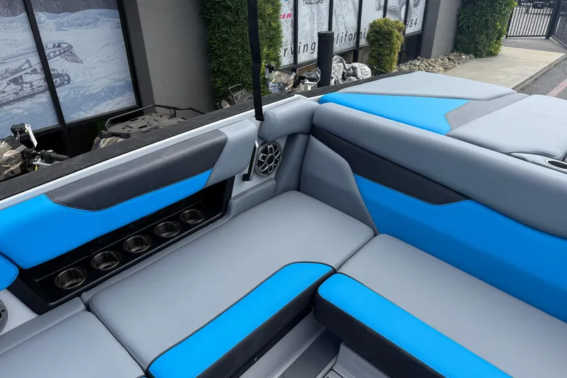 Slide: The Image of 2023 Axis A24 boat interior with blue and gray seating, cup holders, and speaker. - 18