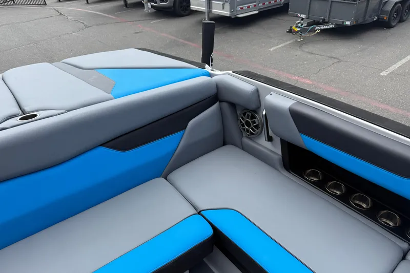 Slide: The Image of 2023 Axis A24 boat interior with blue and gray seating, cup holders, and speaker. - 20