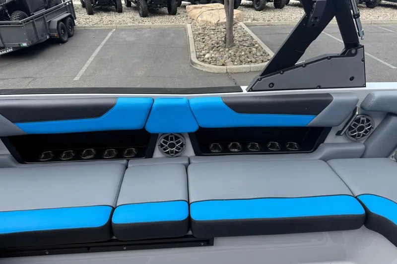 Slide: The Image of 2023 Axis A24 boat interior with blue and gray seating, cup holders, and speakers. - 21