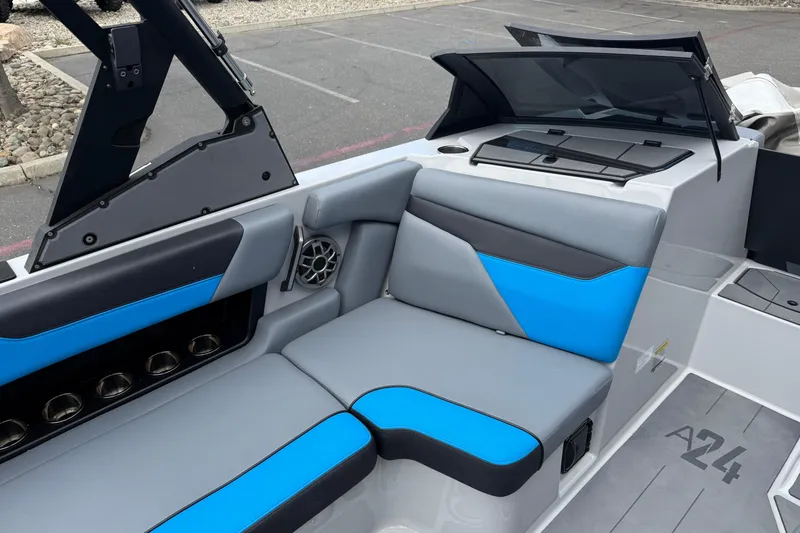 Slide: The Image of 2023 Axis A24 boat interior with blue and gray seating, cup holders, and speaker. - 22