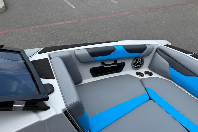 Slide: The Image of 2023 Axis A24 boat interior with blue and gray seating, cup holders, and speaker. - 24