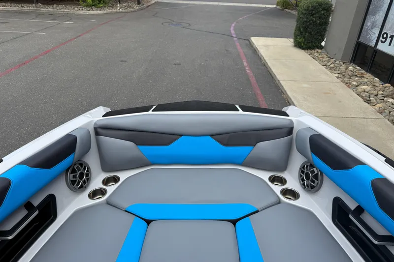 Slide: The Image of 2023 Axis A24 boat interior with blue and gray seating, cup holders, and speakers. - 25