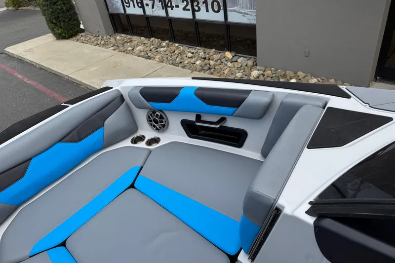 Slide: The Image of 2023 Axis A24 boat interior with blue and gray seating, speaker, and cup holders. - 26