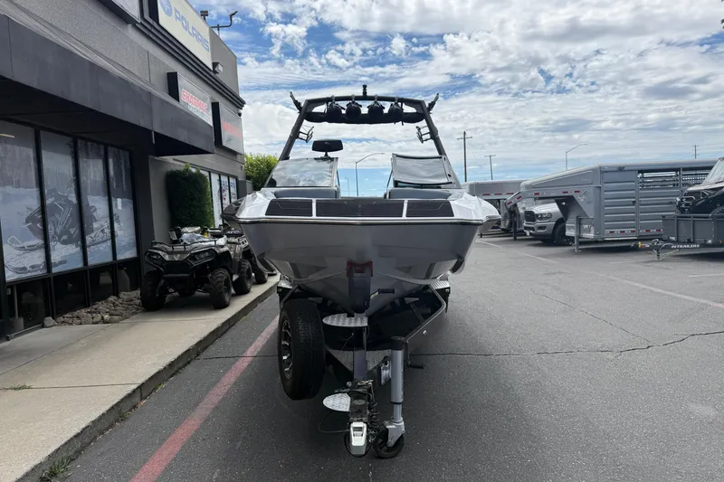 Slide: The Image of 2023 Axis A24 boat on trailer outside dealership, clear sky background. - 6