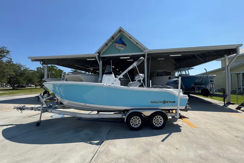 The Image of 2026 NauticStar 212 Legacy boat on trailer, parked outside a covered storage area. - 1
