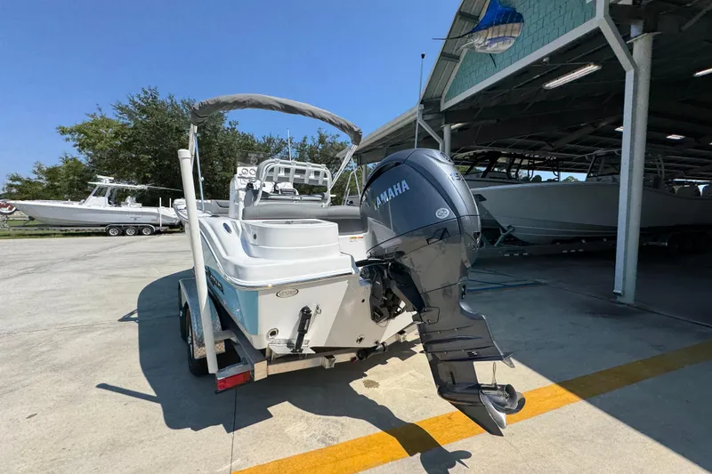 Slide: The Image of 2026 NauticStar 212 Legacy boat with Yamaha engine, parked near a marina. - 13