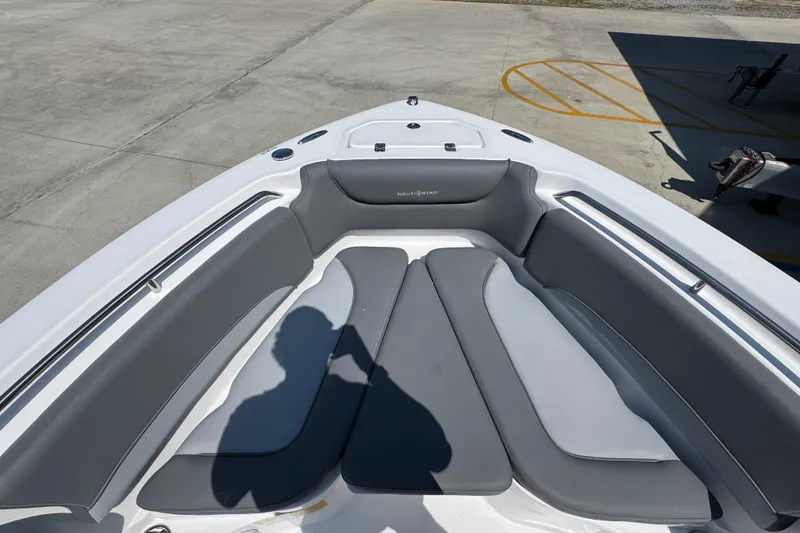 Slide: The Image of 2026 NauticStar 212 Legacy boat with gray cushioned seating in a marina setting. - 17