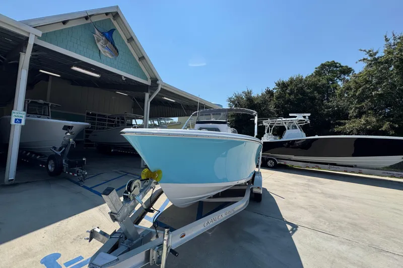 Slide: The Image of 2026 NauticStar 212 Legacy boat on trailer at marina under clear blue sky. - 4